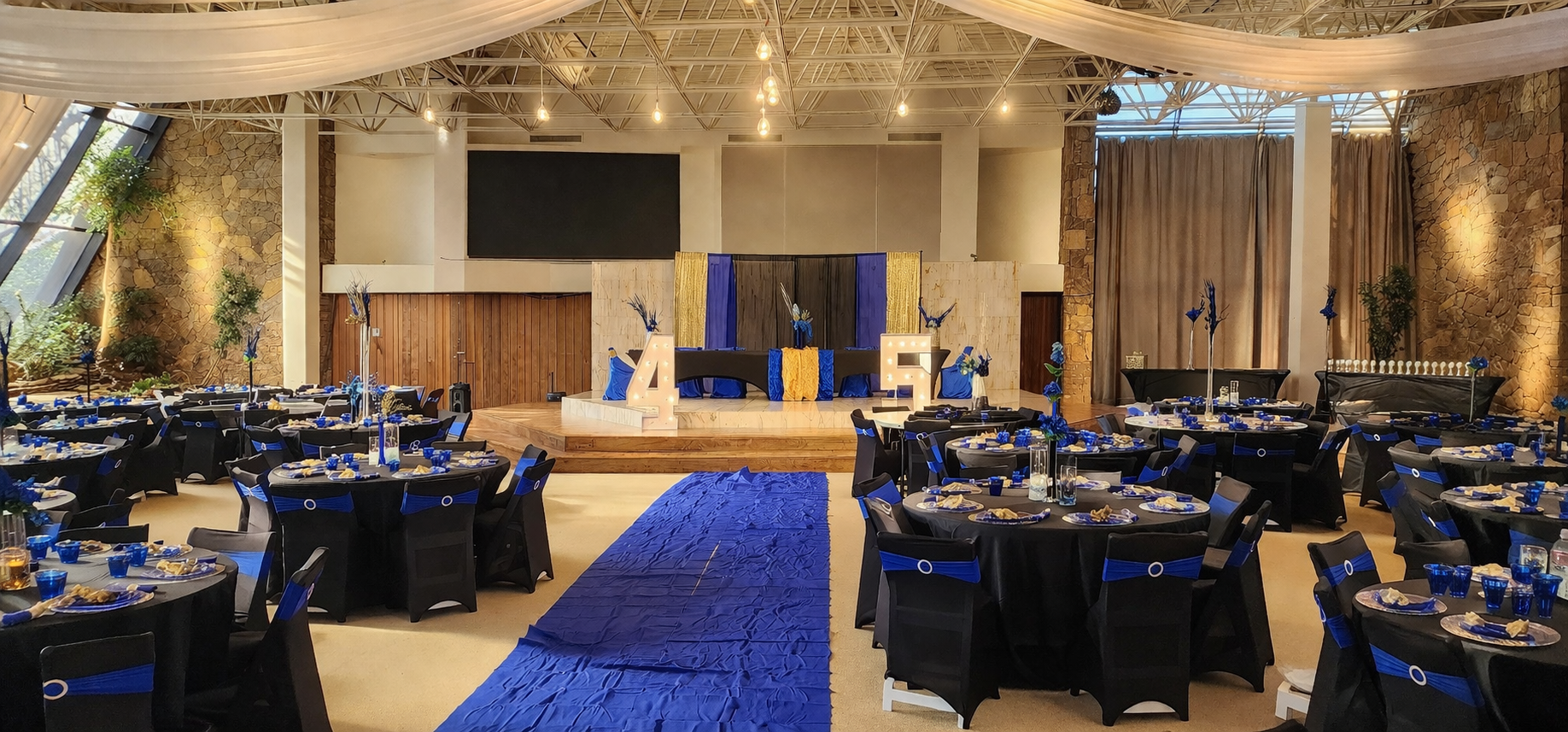 Banquet setup at Oasis Grand Hall with royal blue accents, draped ceiling fabric, and illuminated marquee letters